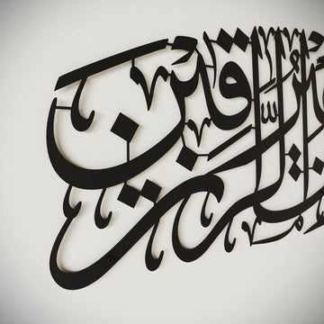 Gros plan de côté sur la calligraphie en métal noir du Dua pour le rizq, bords découpés et vis murales visibles