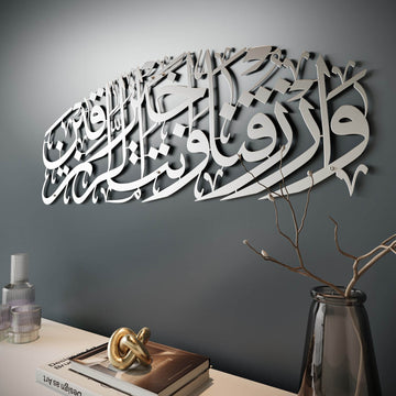Art mural en métal argenté mat Dua pour le rizq, vue en angle rapprochée sur mur gris foncé avec un vase en dessous