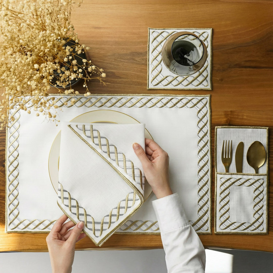 Eternal Weave gold and silver interlocking border placemat with napkin on a plate, overhead view with hands