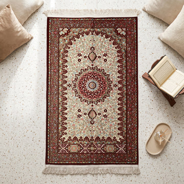 Floral Vine Prayer Rug in Burgundy - Cream, top view on the floor next to a Quran stand and cushions