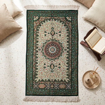 Floral Vine Prayer Rug in Emerald Green - Cream, top view on the floor next to a Quran stand and cushions