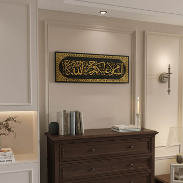 Gold on black glass Assalamu Alaikum wall art, wide view over a dresser in a paneled room
