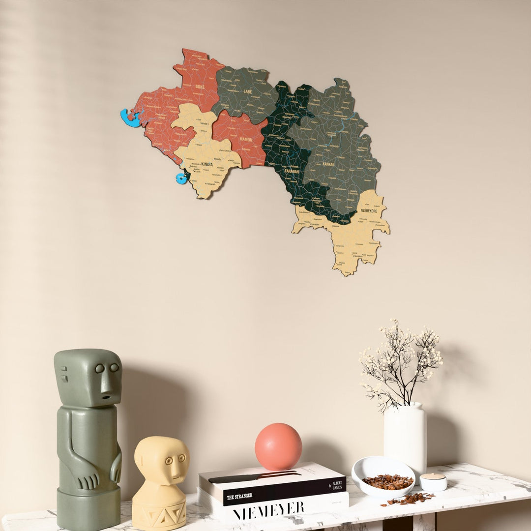 Sage Guinea wooden wall map on a beige wall above a console with figurines