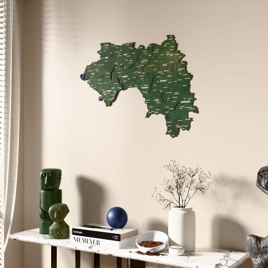 Satellite Guinea wooden wall map beside a sheer curtain, angled view