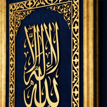 لقطة مقربة بزاوية لحروف كلمة التوحيد الأولى الذهبية وحافة الإطار الذهبي على مخمل أزرق
