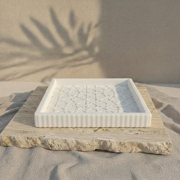 Niedrige Seitenansicht des maurischen Steinrelief-Tabletts mit erhabenem Rand auf einer Travertinplatte