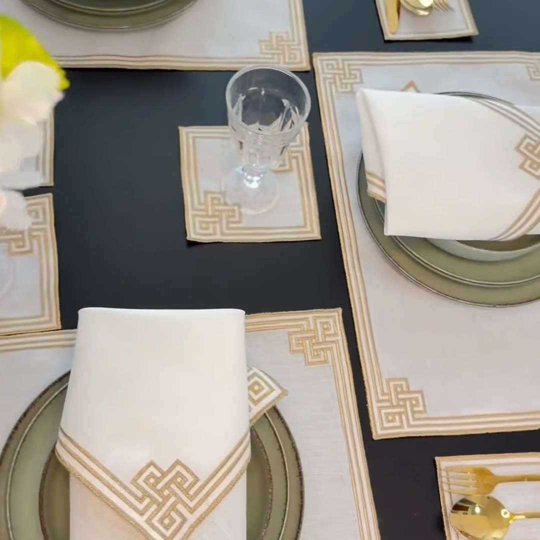 Sets de table et serviettes de Ramadan blanc et doré sur une table à manger sombre