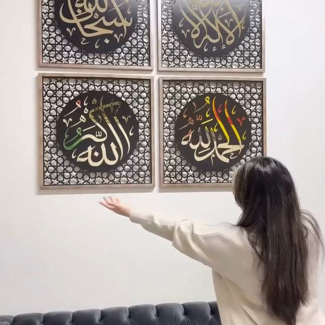 Femme montrant quatre panneaux de calligraphie de dhikr colorés et encadrés