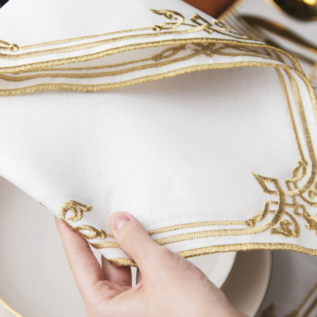 Close-up of the Gold interlocking scroll napkin corner held over a plate