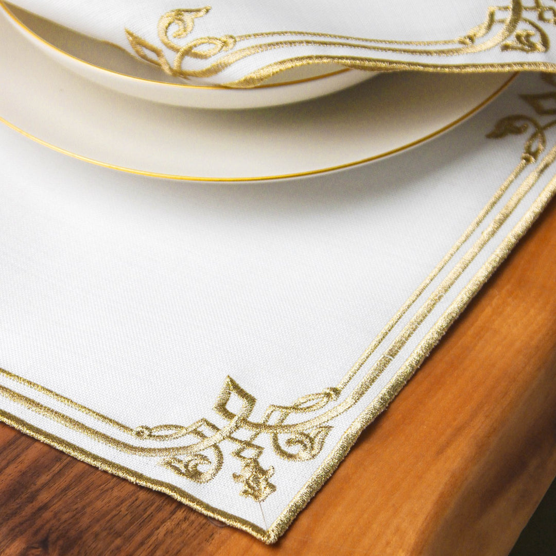 Corner of the Gold interlocking scroll border placemat under a plate on a wooden table