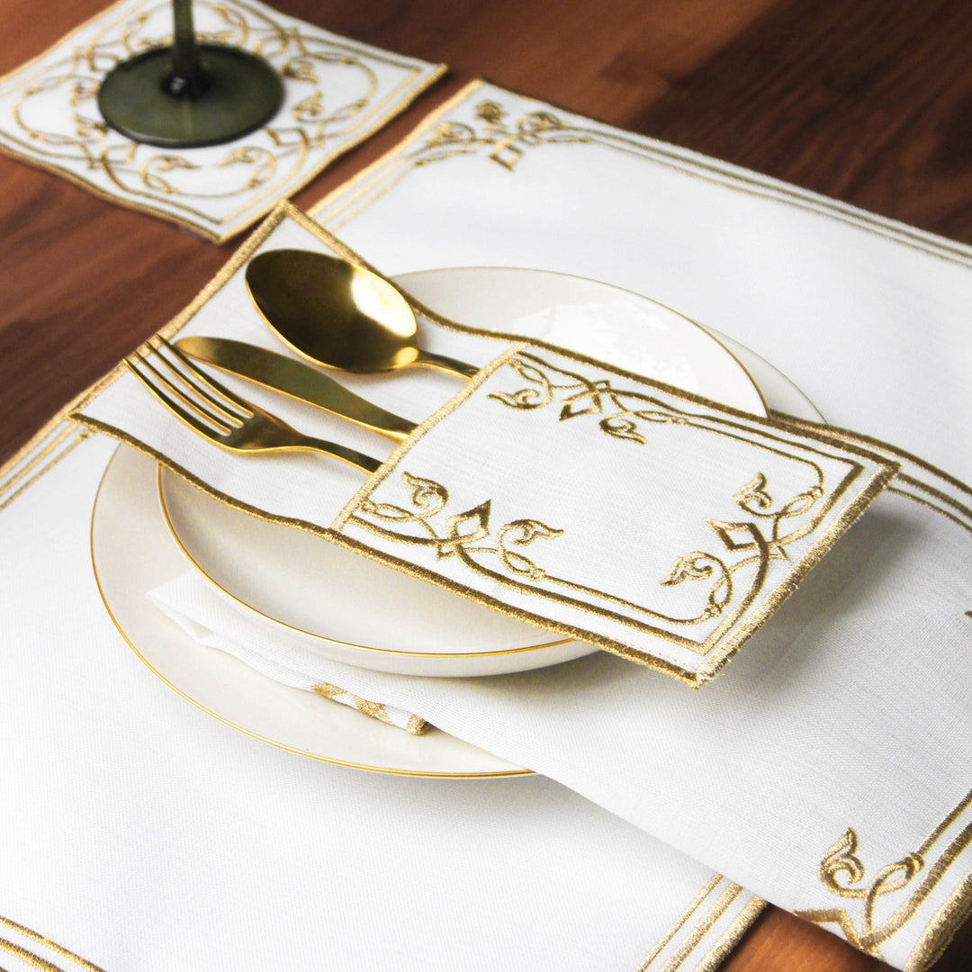 Gold interlocking scroll cutlery pouch with gold spoon and fork resting on a plate