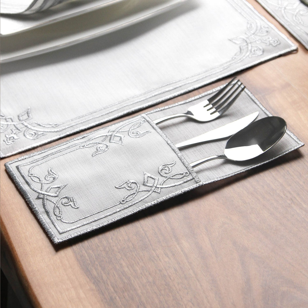 Silver interlocking scroll cutlery pouch holding a fork, knife and spoon on a wooden table
