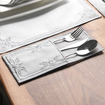 Silver interlocking scroll cutlery pouch holding a fork, knife and spoon on a wooden table