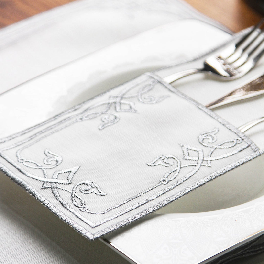Close-up of the Silver interlocking scroll embroidery on the cutlery pouch over a plate