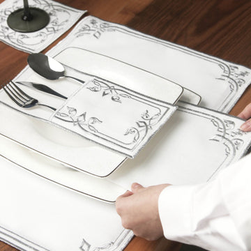 Hand adjusting the Silver interlocking scroll cutlery pouch on a square plate over the placemat