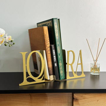 Gold IQRA Latin letter bookends with books, side view with a reed diffuser