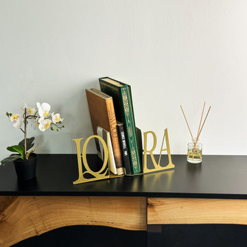 Gold IQRA Latin letter bookends and books, distant view on a black cabinet