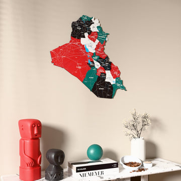 Flag colored Iraq wooden wall map on a beige wall above a console with figurines