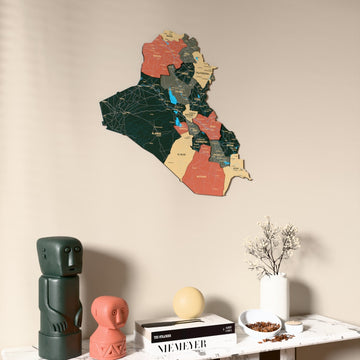 Sage Iraq wooden wall map on a beige wall above a console with figurines