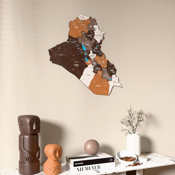 Soil Iraq wooden wall map on a beige wall above a console with figurines