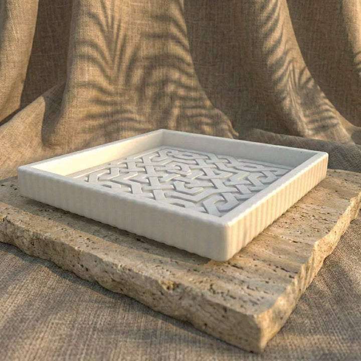 Decorative stone tray with intricate carvings on a textured fabric background