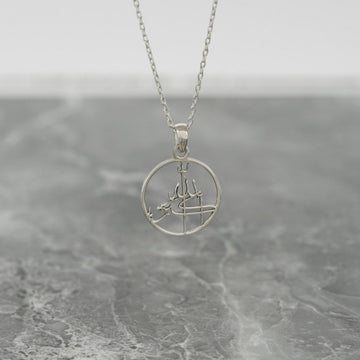 Silver Allahu Akbar Islamic necklace with a round pendant hanging above gray marble