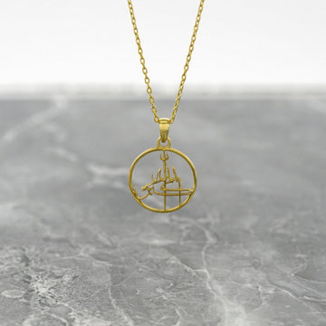 Gold Allahu Akbar Islamic necklace with a round pendant hanging on a gray marble surface