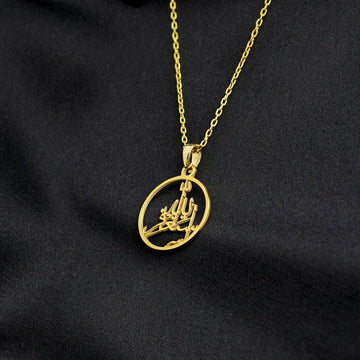 Gold Astaghfirullah pendant tilted on its chain, draped over black fabric