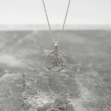 Silver Astaghfirullah Islamic necklace with a round pendant hanging above gray marble