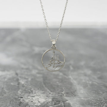 Silver Hasbiyallah Islamic necklace with a round pendant hanging above gray marble