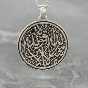 Gros plan du pendentif Mashallah La Quwwata Illa Billah argenté avec calligraphie arabe gravée