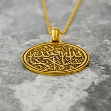 Disque du pendentif Mashallah La Quwwata Illa Billah doré en angle, montrant la calligraphie gravée