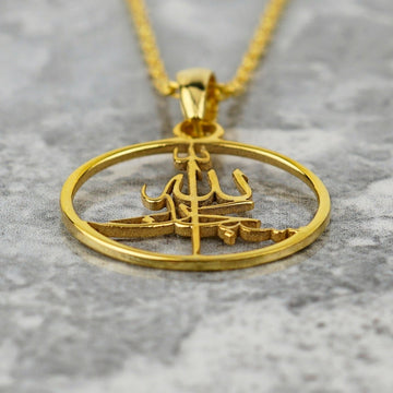 Close-up of the gold Subhanallah pendant at an angle on marble, showing the cut-out calligraphy