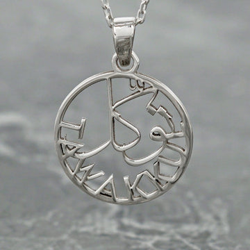 Close-up of the silver Tawakkul pendant with Arabic calligraphy and the word TAWAKKUL around the ring
