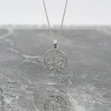 Silver Tawakkul Islamic necklace with a round pendant hanging above gray marble