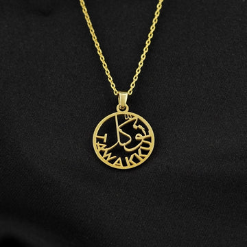 Gold Tawakkul Islamic necklace with a round pendant of Arabic calligraphy and Latin letters on black fabric
