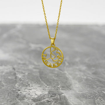 Gold Tawakkul Islamic necklace with a round pendant hanging on a gray marble surface