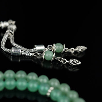 Silver-tone tassel with two green aventurine accent beads and leaf-shaped ends on the Islamic rosary