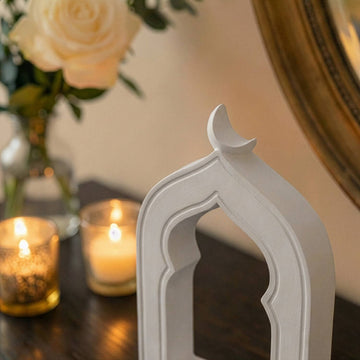 Close-up of the mihrab stone arch's crescent top and hollow window with candles behind