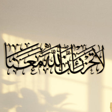 لوحة جدارية معدنية سوداء لسورة التوبة الآية 40، منظر مائل للخط العربي وظله
