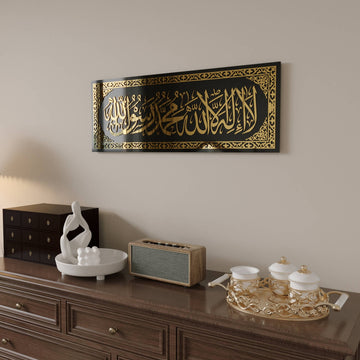 منظر مائل للوحة زجاجية لكلمة التوحيد بأكريليك ذهبي يُظهر انعكاس الزجاج الأسود اللامع