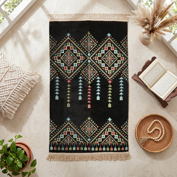 Kilim Prayer Rug in Black, top view on the floor next to a Quran stand and cushions