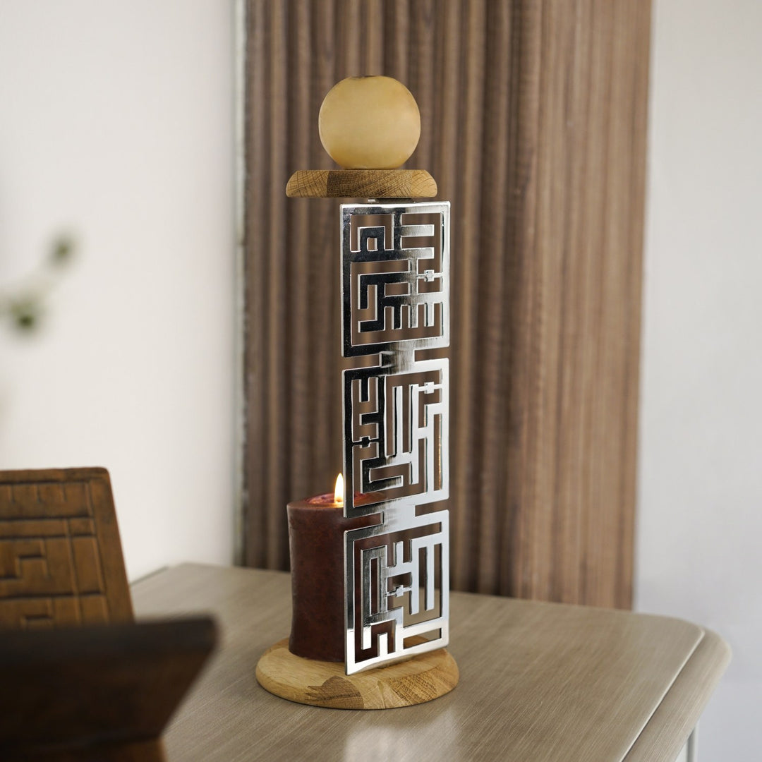 Glänzend silberner Kufi-Kerzenhalter mit brennender Kerze auf einem Beistelltisch, Vorhang im Hintergrund