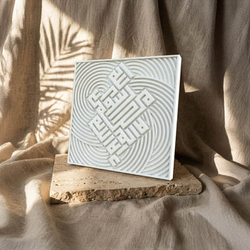 Carreau en relief de pierre blanche première Kalima en calligraphie coufique, vue en angle avec ombres de palmes