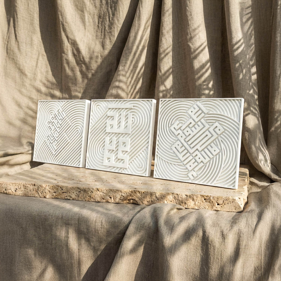 Ensemble de trois carreaux coufiques en relief de pierre blanche alignés sur une dalle, vue depuis la gauche