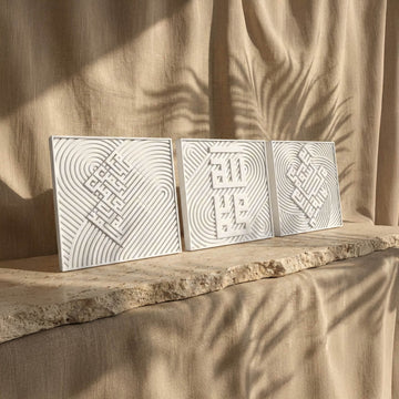 Ensemble de trois carreaux coufiques en relief côte à côte sur une étagère en pierre, vue de face