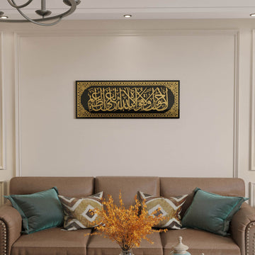 Gold acrylic La hawla wa la quwwata illa billah glass wall art centered above a sofa on a paneled wall