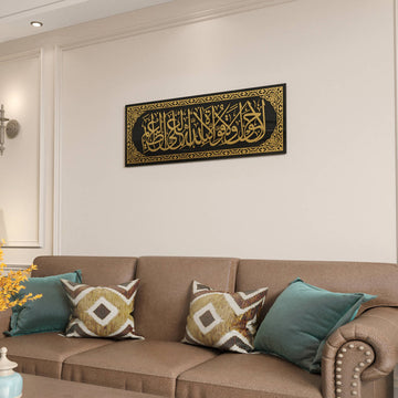 Gold acrylic La hawla wa la quwwata illa billah glass wall art above a brown sofa, cropped view