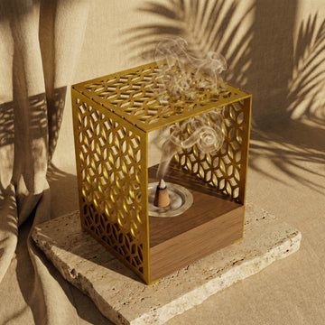 Wooden base mabkhara with a gold Petal Lattice metal frame and incense smoke, on a stone slab