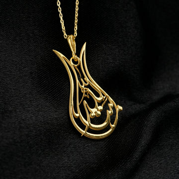 Gold Tulip Mashallah pendant angled to catch the light, black background